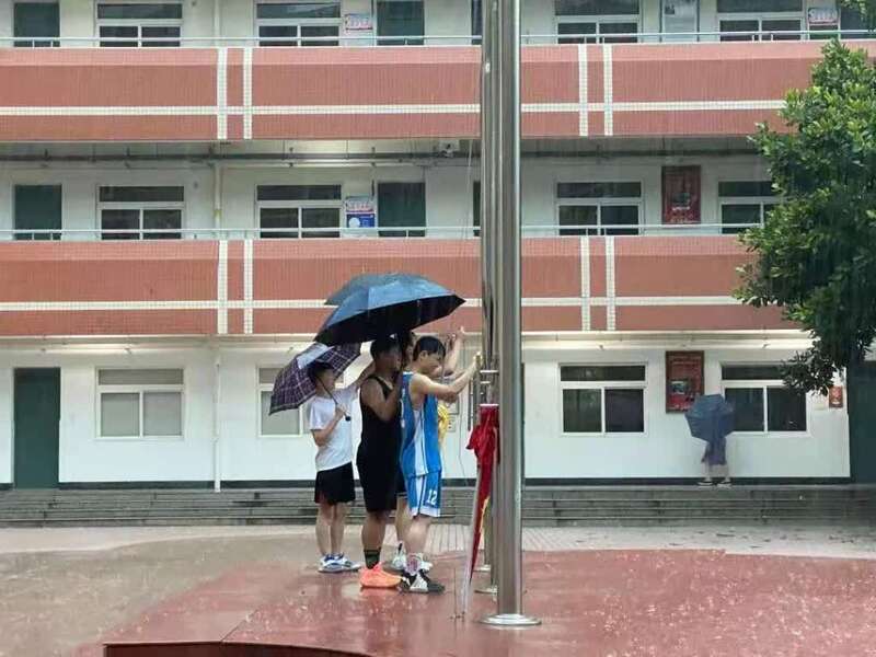 少年暴雨中收起国旗